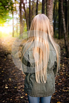 Girl with long blonde hair from behind outside in the forest photo