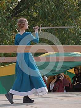 A girl in a long dress demonstrates her sword skills