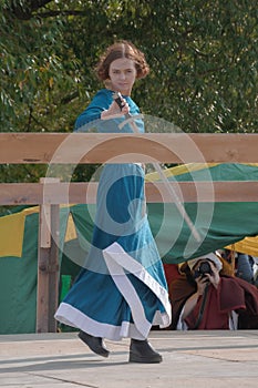 A girl in a long dress demonstrates her sword skills