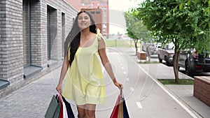 A girl in a long dress goes around the city after shopping having a good mood. 4K