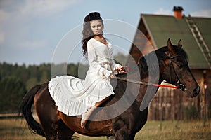 Girl in a long dress riding a horse, a beautiful woman riding a horse in a field in autumn. Country life and fashion, noble steed