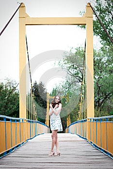 Girl with long hair and curls in a dress standing on suspension