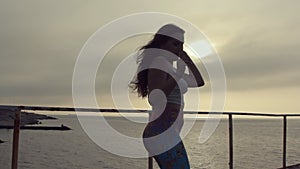 Girl with long hair dressed in leggings incendiary dances on the pier near the sea at the sunset