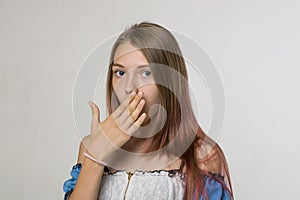 A girl with long hair holds her palm at her mouth.Portrait close-up