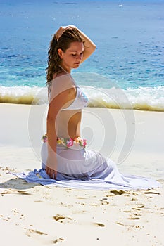 Girl with long hair sitting on sand beach