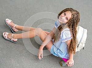 Girl with long hair sitting on skating board