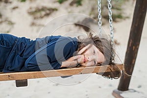 Girl with long hair on a swing on the beach in summer