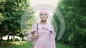 Girl in long purple dress and hijab wanders along park