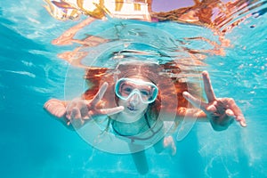 Girl with long red hair show v gesture underwater