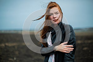 A girl with long red hair stares intently into the distance.