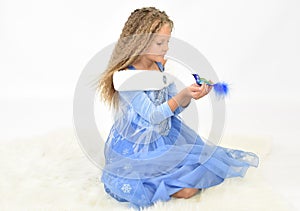 girl with long wavy hair in a blue winter dress on a white long-haired rug