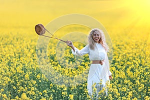 A girl in a long white dress admiring the dawn or sunset in the bright yellow field.