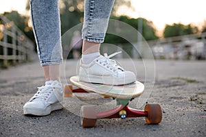 Girl with longboard wearing sneakers shoes in urban style