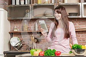 Girl look at the tablet.Young Woman Cooking in the kitchen at home. Healthy Food.