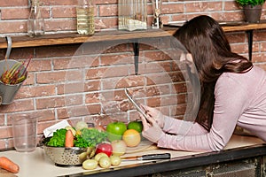 Girl look at the tablet.Young Woman Cooking in the kitchen at home. Healthy Food.