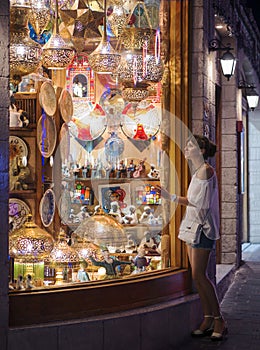 Girl look through the window of souvenir shop at eastern bazaar in Egypt