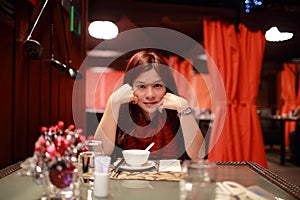 Girl  look at you face to face, she rest her chin on the hand, waiting the dinner in the romantic restaurant in hong kong