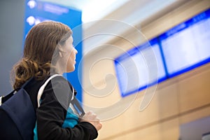 Girl looking at airport flight information board