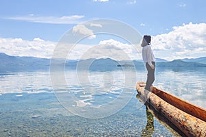 Girl looking aside standing on canoe, back to camera