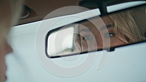 Girl looking automobile mirror enjoying beauty close up. Blonde checking makeup.