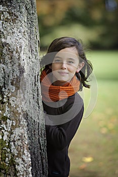 Girl looking from behind a tree