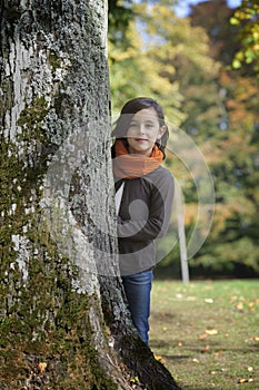 Girl looking from behind a tree