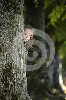 Girl looking from behind a tree