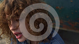 Girl looking camera blowing curly hair from face close up. Woman shaking curls.