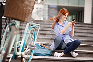 Girl looking in cell phone while pausing in town photo