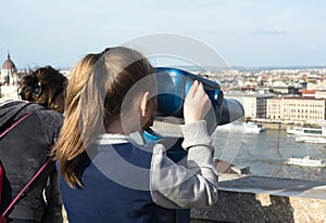 Girl looking at coin operated binocular in Budapest