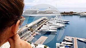 Girl looking at cruise liner from hotel terrace, waiting for embarkation on ship