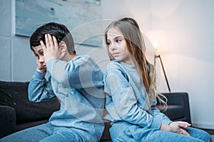 Girl looking at emotional brother with hands on head at home