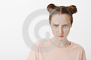 Girl looking at enemy, feeling scorn and anger, looking from under forehead at camera and frowning, standing serious and