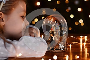 Girl looking at a glass ball with a scene of the birth of Jesus Christ