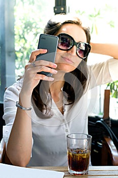 Girl looking at her smartphone and taking a selfie with glasses - telecommunication advertising
