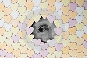 Girl looking through hole in wall of heart-shaped sweets