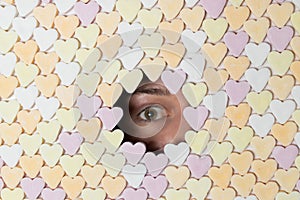 Girl looking through hole in wall of heart-shaped sweets