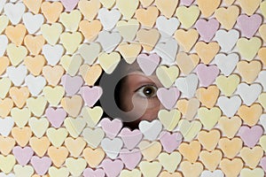 Girl looking through hole in wall of heart-shaped sweets