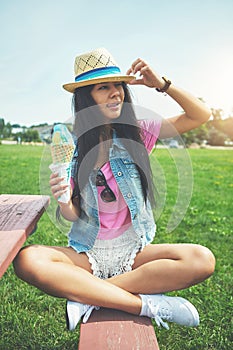 Girl, looking and ice cream cone at park sitting on bench with vanilla or bubblegum flavor for summer. Woman, happy and