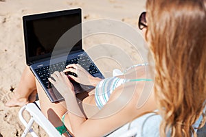 Girl looking at laptop on the beach