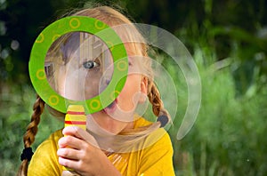 Girl looking through a magnifying glass