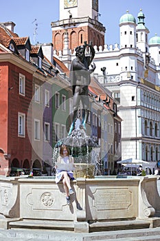 girl looking at the map sitting by the fountain at the main square Rynek of Poznan photo