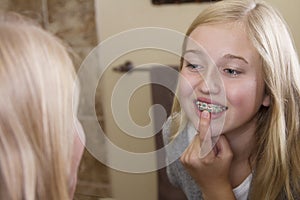 Girl looking in the mirror, examining her braces