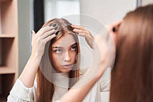 Girl looking in the mirror at her scalp