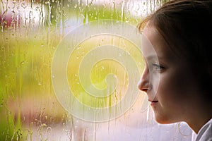 Girl looking out rainy window