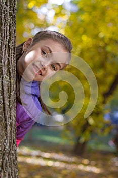 Girl looking out tree in autumn park
