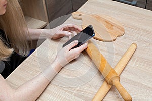 The girl is looking on the phone for a recipe for making bread products from flour