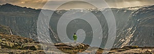 Girl looking at a picturesque view of the  fjord underneath close to Trolltunga