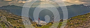 Girl looking at a picturesque view of the  fjord underneath close to Trolltunga