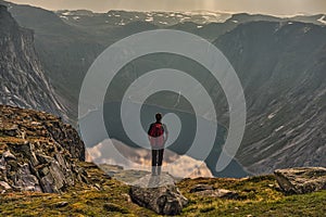 Girl looking at a picturesque view of the  fjord underneath close to Trolltunga